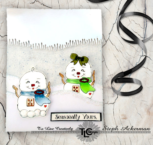 Two little snow babies sitting on a hill!  The greeting card says Seasonally yours, and is simply a delightful project that includes a twist on the use of the grassy die from TLCDesigns.shop.  Turn the paper cut upside down on silver paper and it turns into a delightful icicle display!  Simple and fun Holiday greeting cards!