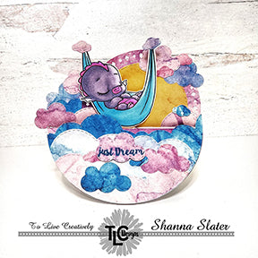 This rocker card full of puffy clouds is a penny rocker with Dreamer Dragon swinging in his hammock! The stamps and dies including the Aztec Sunshine die set are from TLCDesigns.shop