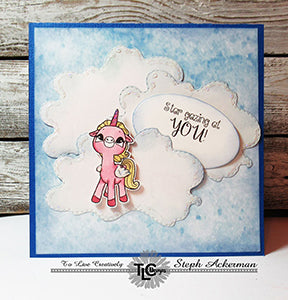 Beautiful and puffy looking clouds designed from the Cherry On Top Die set from TLCDesigns.shop on this pretty in sky blue greeting card. The Alicorn stamped image colored in pink is Star gazing at YOU! as the sentiment says!