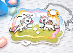 The Alicorn Happiness stamps from TLCDesigns.shop used with the Interactive die called See You In The Center designed with sweet pink and blue spring and Easter colors! The little field scene is the perfect backdrop for these adorable images